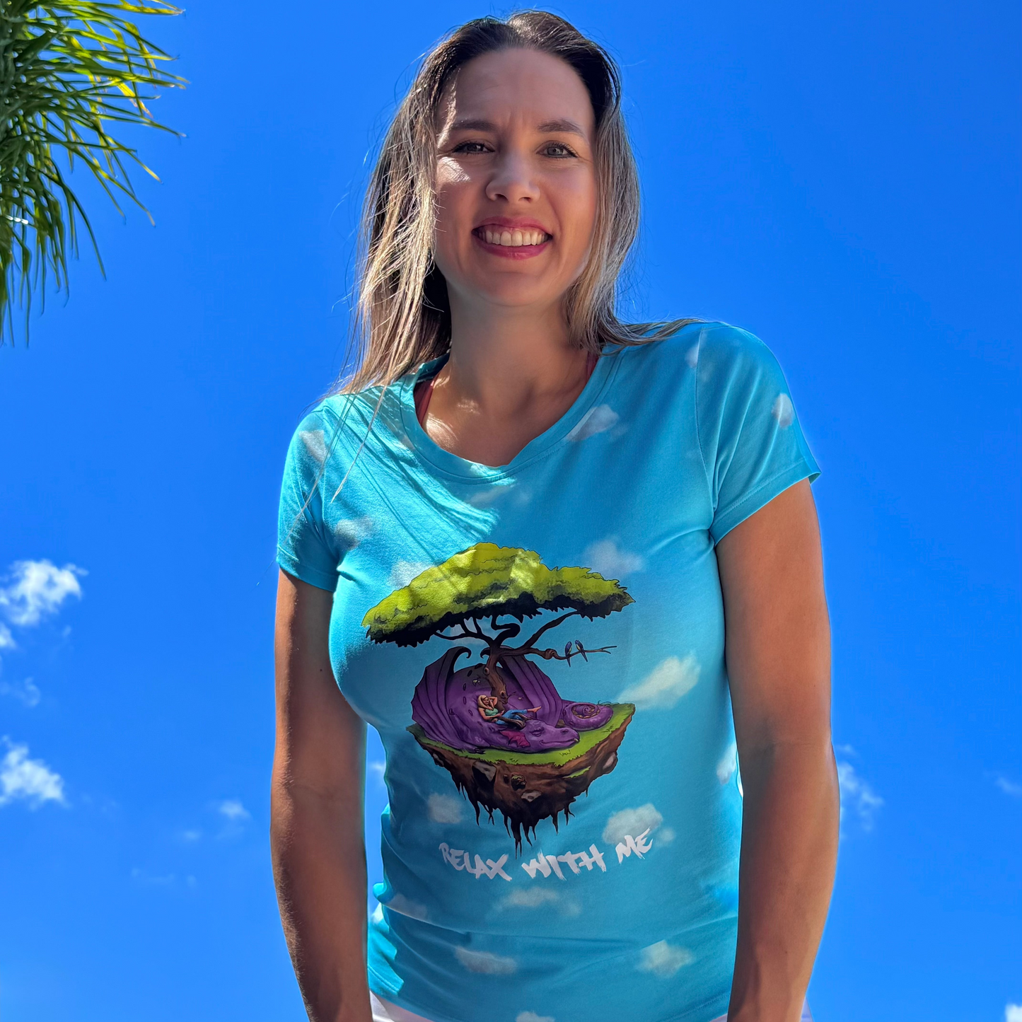 Woman wearing a blue t-shirt with a colorful graphic design against a clear blue sky.