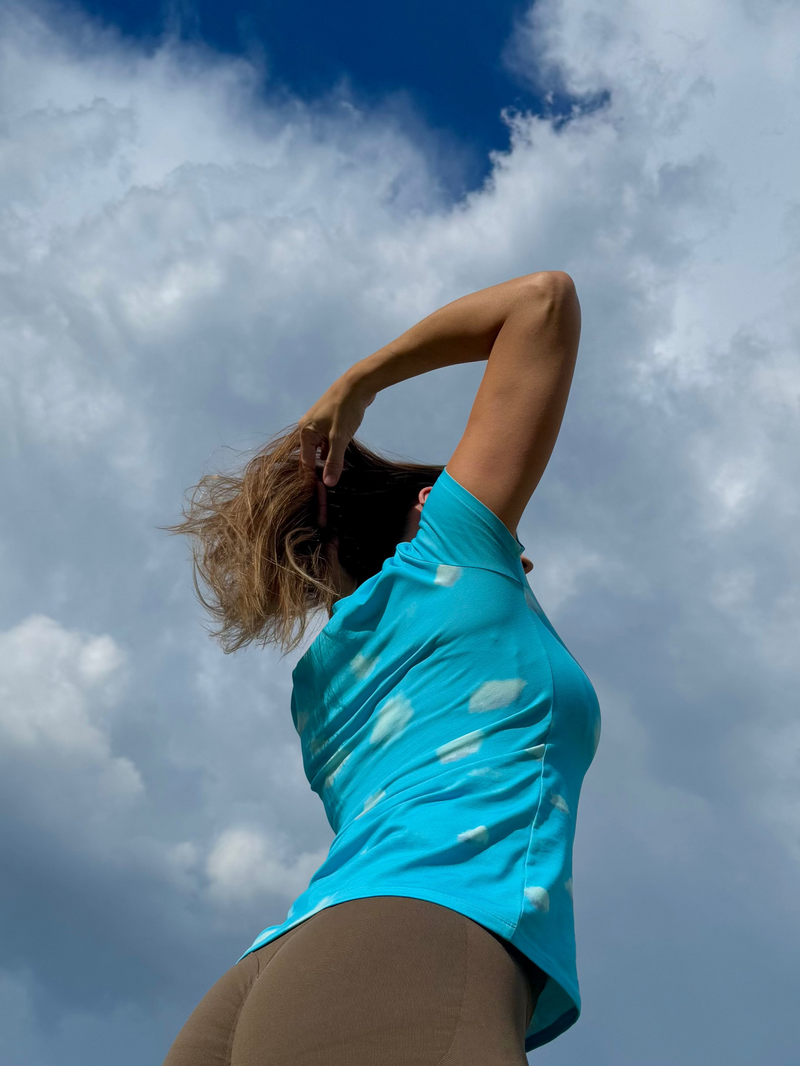 Person wearing a blue shirt with cloud patterns against a cloudy sky