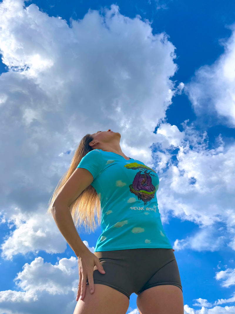 Person wearing a blue t-shirt with a graphic design against a blue sky with white clouds