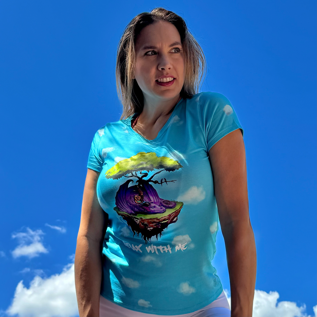 Woman wearing a blue t-shirt with a colorful graphic design against a blue sky.