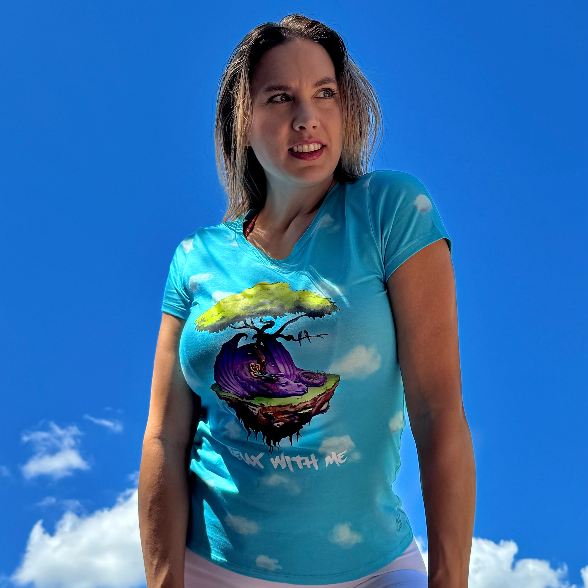 Woman wearing a blue t-shirt with a colorful graphic design against a blue sky.
