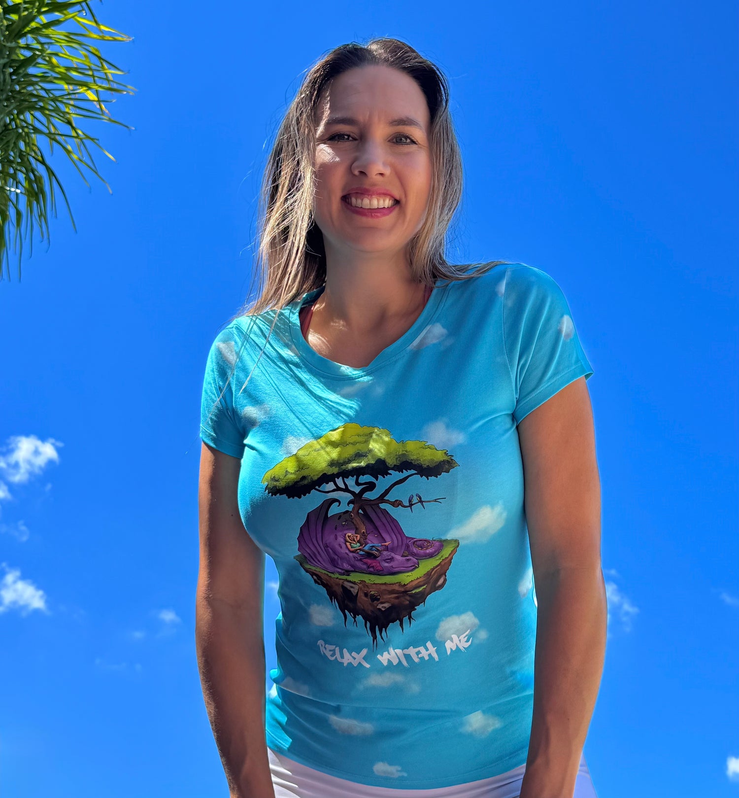 Woman wearing a blue t-shirt with a colorful graphic design against a clear blue sky.