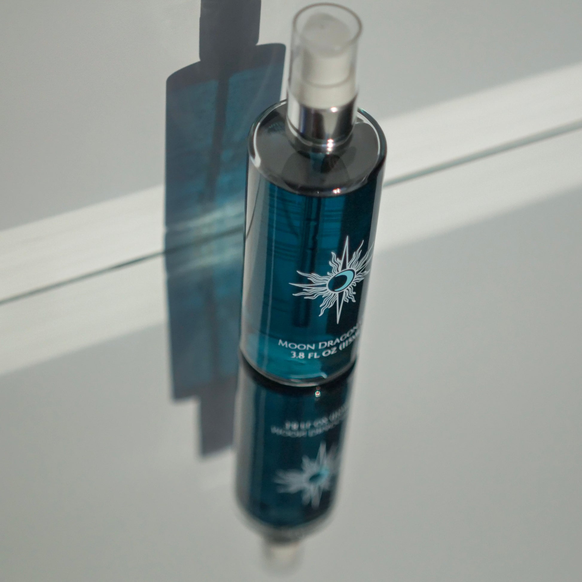 Blue bottle with silver nozzle on a reflective surface